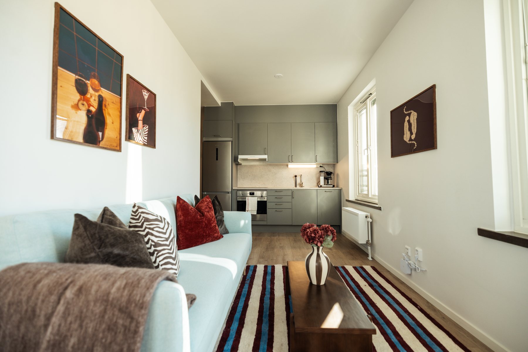 Soffa med kuddar och pläd under två tavlor